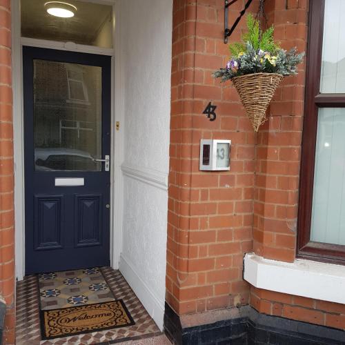 a blue door on a brick building with a basket of flowers at Hollis House - 5 Bedroom Contractor Accommodation in Derby in Derby