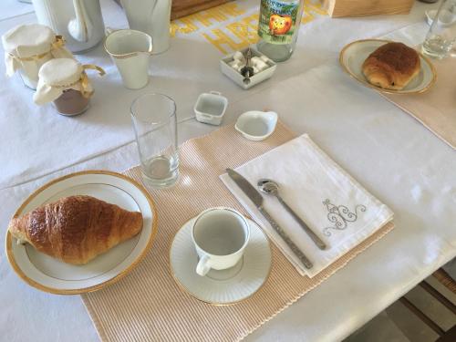 een tafel met borden en kopjes koffie en brood bij La Huberdière in Fondettes