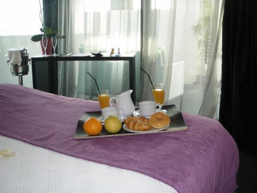 a tray of fruit and orange juice on a bed at Hotel Playa Ribera in Suances
