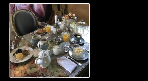 una mesa cubierta con platos y tazas y vasos de zumo de naranja en Manoir de Livet en Saint-Germain-de-Livet