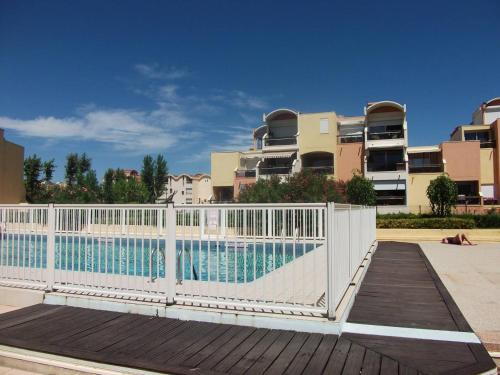 グリュイッサンにあるStudio sur le port, climatisation, wifi, piscine, lave-lingeの建物前のスイミングプール周囲の白い柵