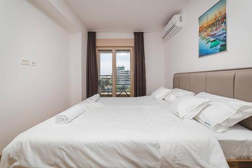 sypialnia z białym łóżkiem z białą pościelą i poduszkami w obiekcie Blue Marlin Apartments w Budvie