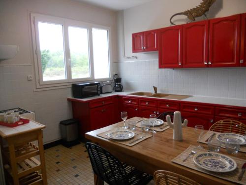 une cuisine avec des placards rouges et une table en bois dans l'établissement LE PETIT SARMENTIN, à Saint-Romain-sur-Cher