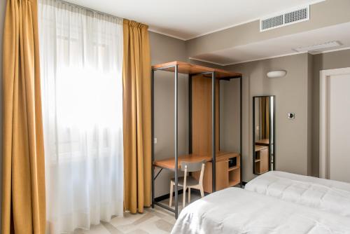 a bedroom with a bed and a desk and a window at APARTHOTEL CASA MIA in Milan
