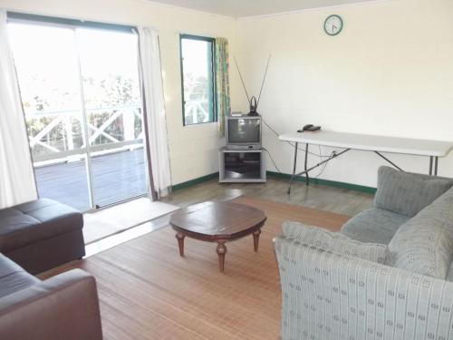 a living room with a couch and a table and a tv at Green Lodge Holiday Homes in Nuku‘alofa