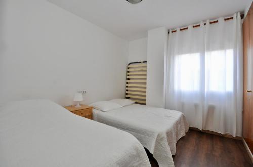リョレート・デ・マルにあるApartment Didierの白いベッドルーム(ベッド2台、窓付)