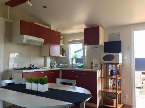 una cucina con mobili rossi e un tavolo e un tavolo e un tavolo di Mobil-Home 4p Privé Camping 5 étoiles Erdeven 7saints a Erdeven