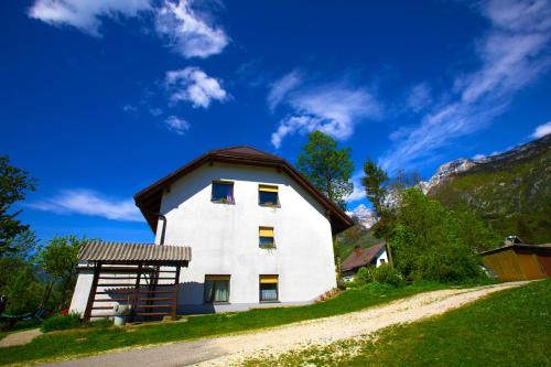 a white house with a brown roof on a hill at Bovec Holiday House in Bovec