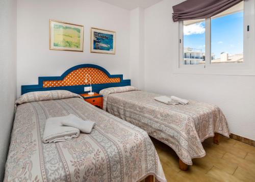 a room with two beds and a window at Apartamentos Charlys Can Picafort in Can Picafort