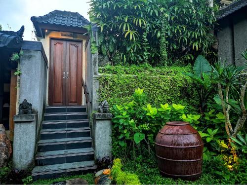 a house with a wooden door and stairs and a barrel at Villa with private pool at Villa Nirvana Ubud in Ubud