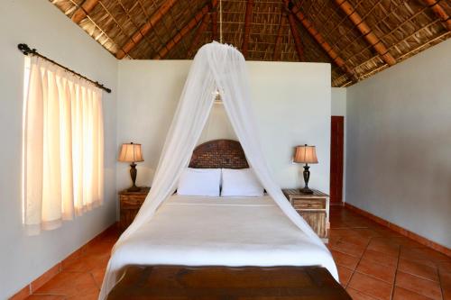 a bedroom with a bed with a mosquito net at Cerritos Surf Town - Beach Front Property in El Pescadero