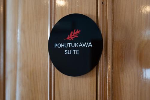 
a black and white sign on a wooden door at The Old Oak Boutique Hotel in Mangonui
