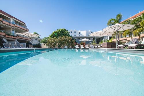 a large swimming pool with chairs and an umbrella at Hotel Laguna in Noosa Heads