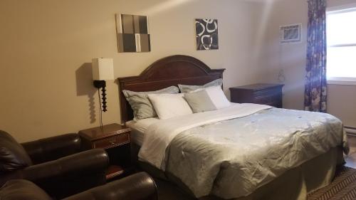 a bedroom with a bed and a leather chair at Rothesay Motel in Rothesay