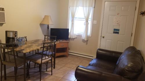 a living room with a table and a leather couch at Rothesay Motel in Rothesay