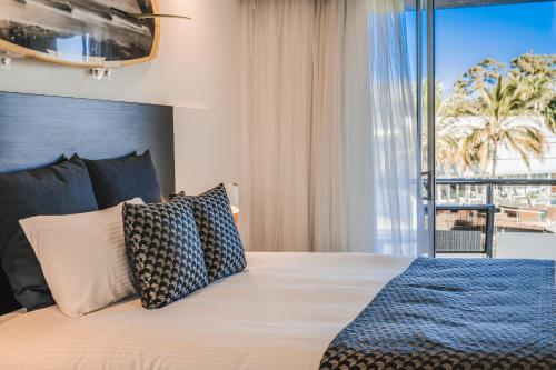 a hotel room with two beds and a large window at Hotel Laguna in Noosa Heads