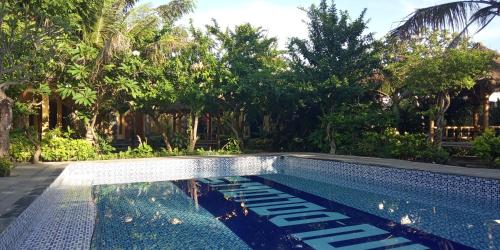 a swimming pool in a yard with trees at Vico hotel in Nusa Dua