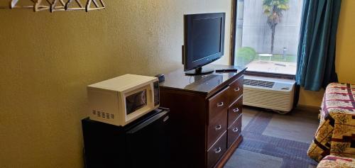a room with a tv on a dresser with a microwave at Red Carpet Inn-Macon in Macon