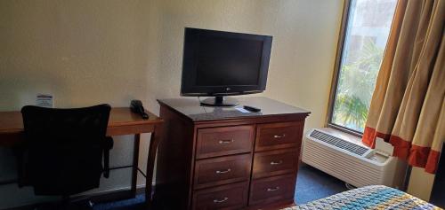 a bedroom with a desk with a television on a dresser at Red Carpet Inn-Macon in Macon