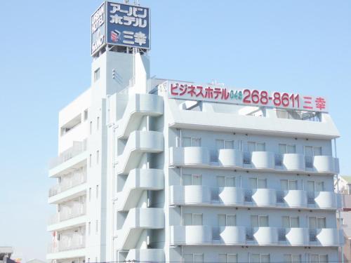 a white building with a sign on top of it at Urban Hotel Sanko in Chiba