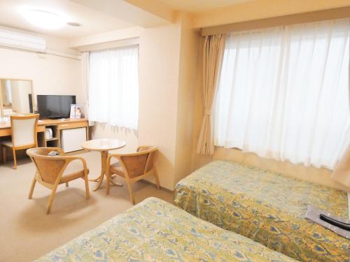 a hotel room with two beds and a table and chairs at Urban Hotel Sanko in Chiba