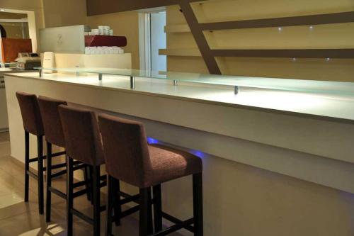 een bar met vier stoelen aan een aanrecht in een keuken bij Piazza Hotel in Villa Carlos Paz