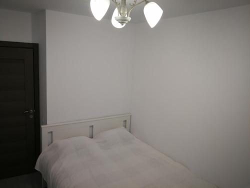a white bed in a white bedroom with a chandelier at Apartament Karina complex Bacovia in Bacău