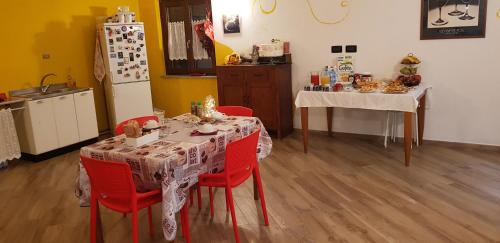 a kitchen with a table with red chairs and a refrigerator at La Corte B&B in Candiolo