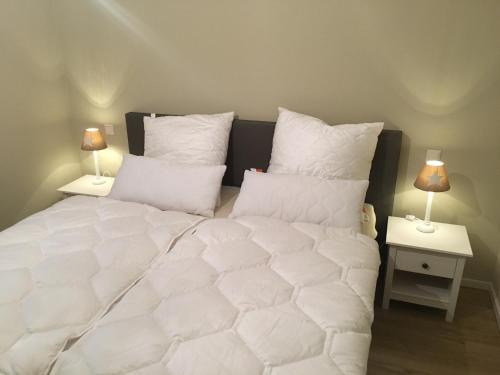 1 cama con sábanas blancas y 2 lámparas en las mesas en Ferienwohnung Möwennest N°3, en Grömitz