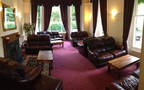 a living room with leather furniture and a fireplace at Broughton Craggs Hotel in Cockermouth