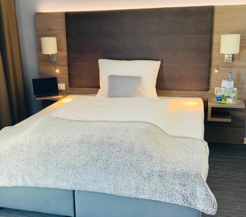 1 dormitorio con 1 cama blanca grande y ordenador portátil en StadtHotel ARTE en Remagen