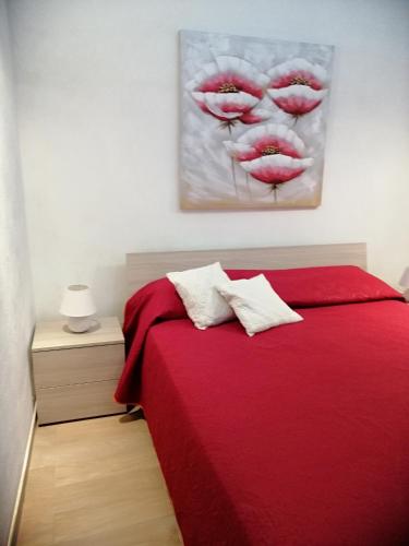 a bedroom with a red bed with a painting on the wall at Casa per Vacanze a Marsala in Marsala