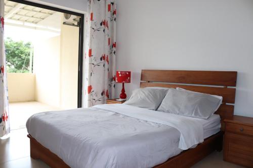 a bedroom with a large bed with a wooden headboard at Mahina Luxury 2 Bedroom Apartment with Pool in Flic-en-Flac