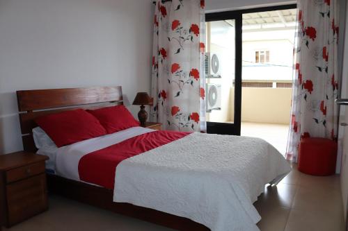 a bedroom with a bed with red pillows and curtains at Mahina Luxury 2 Bedroom Apartment with Pool in Flic-en-Flac