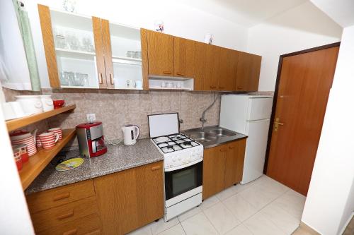 a kitchen with wooden cabinets and a white stove top oven at Apartments Anka in Rtina