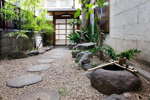 a garden with rocks and a tree and a fence at Ryokan ASAKUSA-chaka- by Tranova in Tokyo