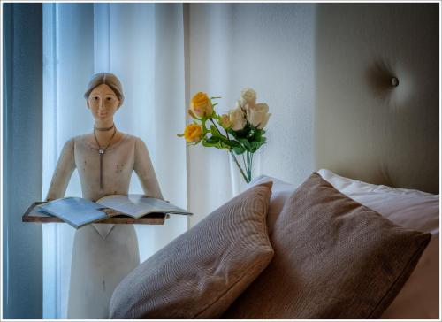 a statue of a man holding a book next to a bed at Villa Aquarius - Larihome A08 in Vercana