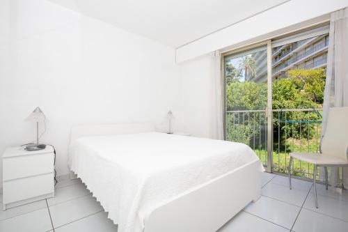 une chambre blanche avec un lit blanc et une fenêtre dans l'établissement Appartement vacances cannes, à Cannes