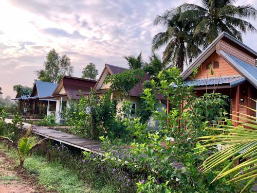 a house with a wooden walkway in front of it at Baan Thung Home Stay in Prasat