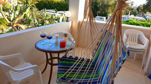 eine Hängematte auf einem Balkon mit zwei Gläsern Wein in der Unterkunft Astrofegia Apartments Near The Sea in Ayia Marina