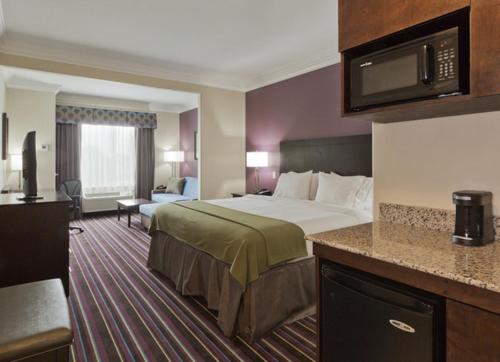 ein Hotelzimmer mit einem großen Bett und einer Küche in der Unterkunft Holiday Inn Express & Suites Raceland - Highway 90, an IHG Hotel in Raceland