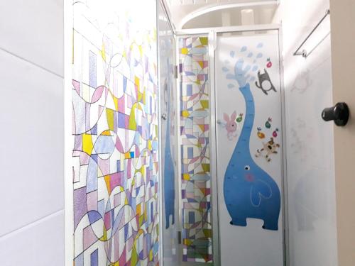 a shower with a glass door with a cat mural at Work Life Balance Busan Station in Busan
