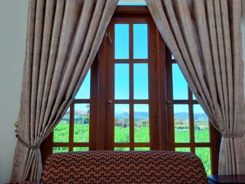 uma janela com cortinas e uma cama em frente em Loversleap bungalow em Nuwara Eliya