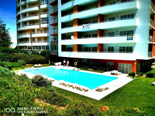 a large building with a swimming pool in front of a building at Apartamento Jeni Residencia Flamingo in Portimão