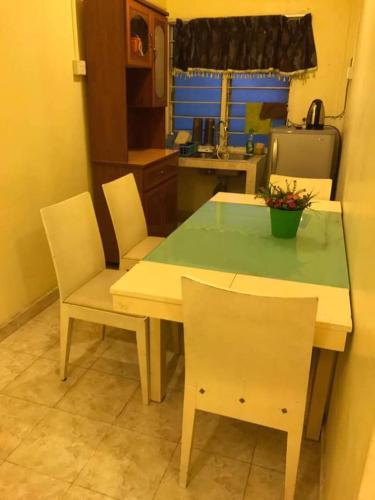 eine Küche mit einem Tisch mit 2 Stühlen und einem Tisch mit grünem Oberteil in der Unterkunft trisya homestay in Kuala Terengganu