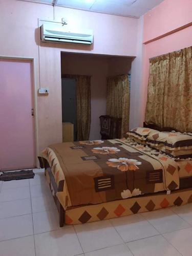 ein Schlafzimmer mit einem großen Bett mit einer braunen Decke in der Unterkunft trisya homestay in Kuala Terengganu