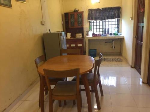 eine Küche mit einem Holztisch mit Stühlen und einem Kühlschrank in der Unterkunft trisya homestay in Kuala Terengganu