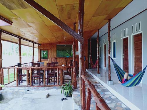a porch with hammocks and a table and chairs at Arthur Homestay Telescope Mentawai in Tua Pejat