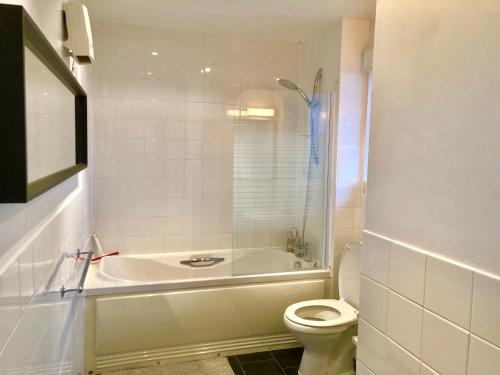 a white bathroom with a tub and a toilet at 2 Bedrooms Modern Apartment, Lounge, Full Kitchen, Balcony, 5 minutes Stratford Station in London