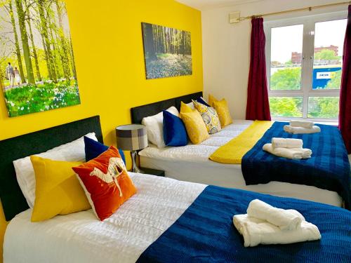 a bedroom with two beds with colorful pillows at 2 Bedrooms Modern Apartment, Lounge, Full Kitchen, Balcony, 5 minutes Stratford Station in London